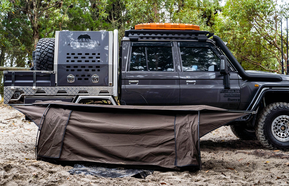 Mr Swagman canvas swag set up on sand beside a dual-cab 4WD ute