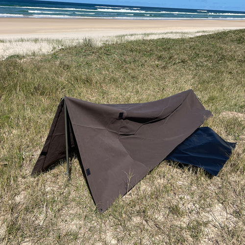 Mr Swagman Classic King Single Swag pitched with two poles on grass behind a beach