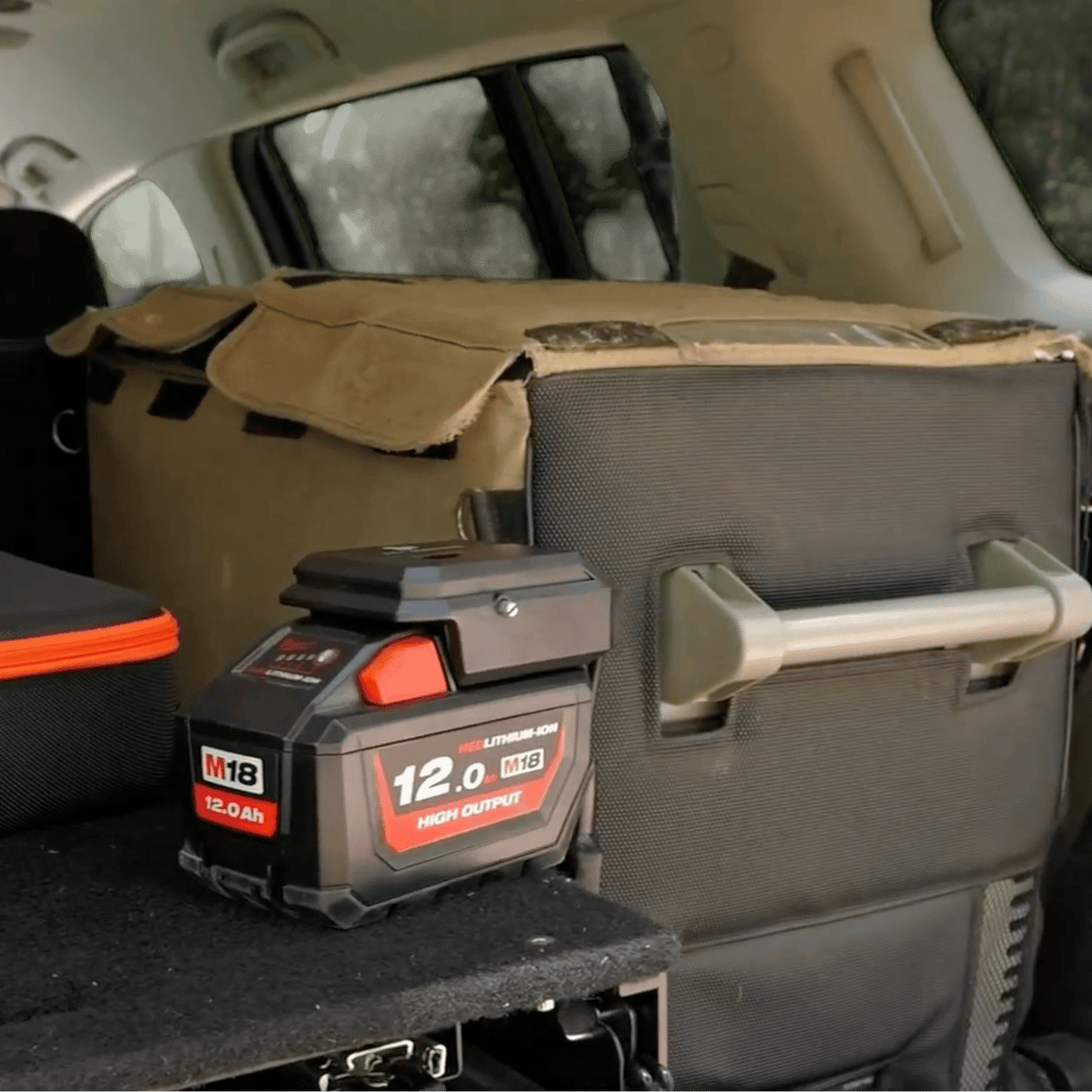 Milwaukee-compatible 18V to 12V Power Supply + Auto Charger Bundle: in use on a battery in the back of a vehicle