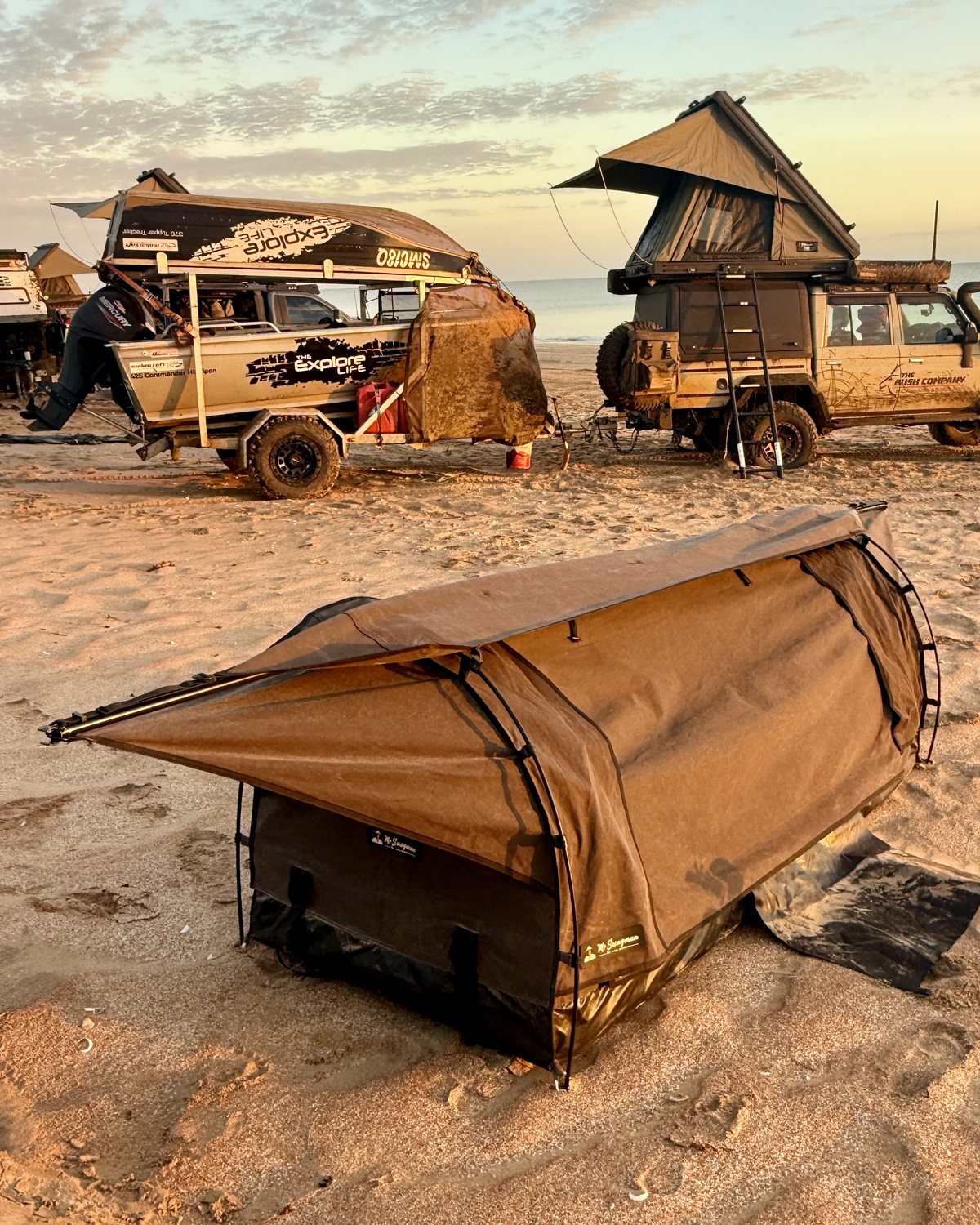 Mr Swagman dome swag on a beach at sunset, with a 4WD and camper trailer behind