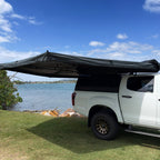 Shelta 270 awning swung out along the side of a ute with a canopy, front three-quarter view
