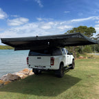 Mr Swagman Shelta 270 awning open around the side and rear of a white ute beside the water
